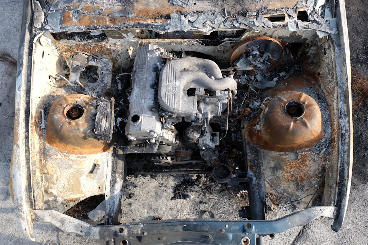 Aerial view of a burnt-out engine in an abandoned car, showcasing rust and decay.